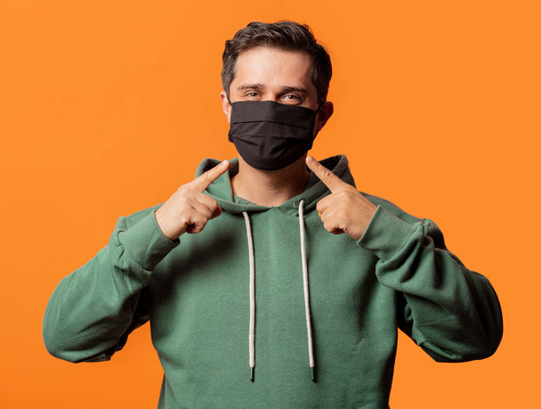 хлопець в масці для обличчя і зелений светр на помаранчевому фоні
 - Фото, зображення