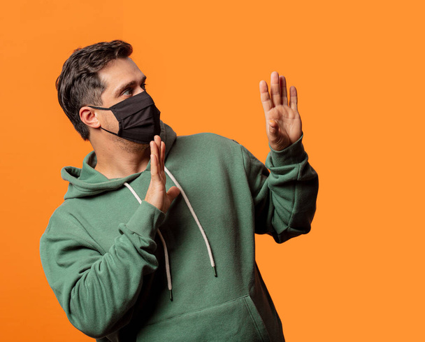хлопець в масці для обличчя і зелений светр на помаранчевому фоні
 - Фото, зображення