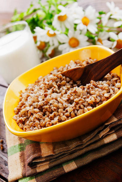 Buckwheat in a bowl on a wooden table - Photo, Image