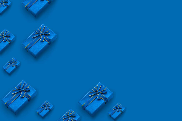 Patroon van geschenkdozen gebonden met een lint op een blauwe achtergrond met kopieerruimte. - Foto, afbeelding