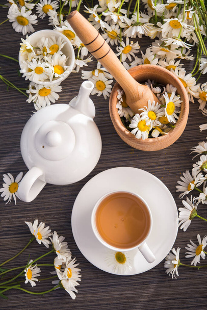 Masasında çiçekler olan bir fincan papatya çayı. Sağlıklı doğal içecek. Üst Manzara. düz yat - Fotoğraf, Görsel