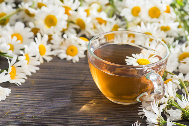 Copo de vidro com chá de ervas com flores de camomila em um fundo de madeira. Bebida saudável. - Foto, Imagem
