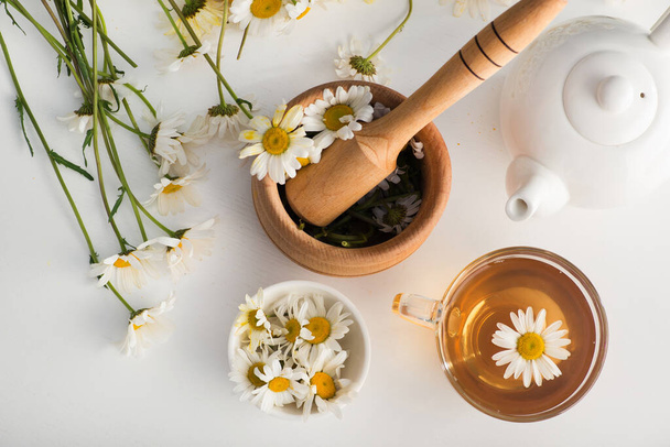 Skleněný šálek s bylinkovým čajem s heřmánkovými květy na bílém pozadí. Zdravý pití. pohled shora. plochý ležel - Fotografie, Obrázek
