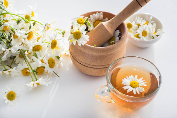 Copo de vidro com chá de ervas com flores de camomila em um fundo branco. Bebida saudável. - Foto, Imagem