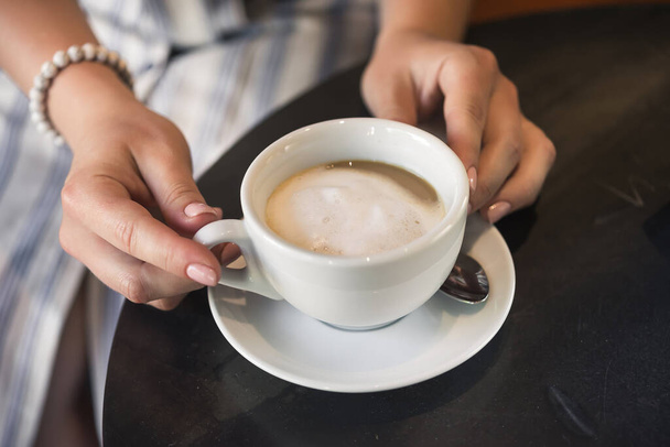 Giovane ragazza in un caffè con una tazza di caffè americano. - Foto, immagini