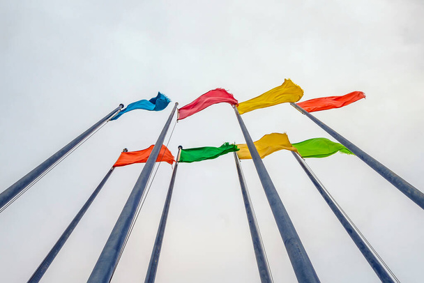 Простой монофонический цвет развешенных флагов на флагштоке, машущих на сером фоне неба - Фото, изображение