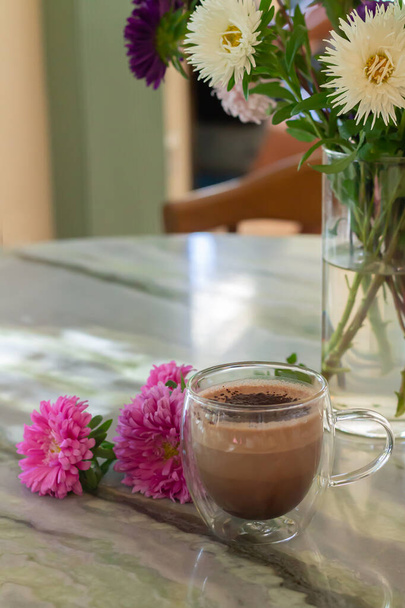 Glasschale mit Kakao neben Blumen auf Cafétisch - Foto, Bild