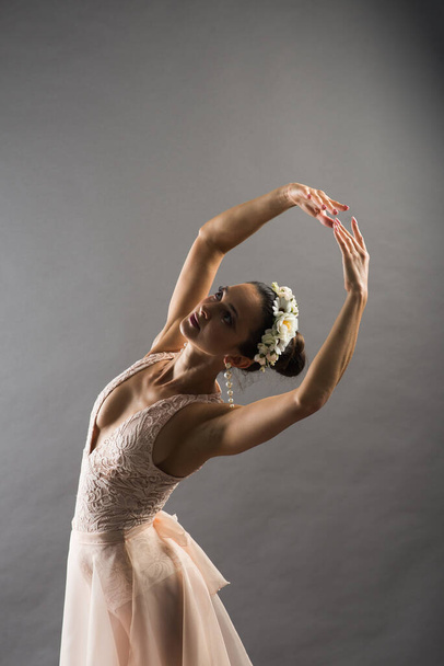 Piękna kobieta baletnica w beżowym stroju kąpielowym pozowanie na punkty na jasnoszarym tle studio - Zdjęcie, obraz