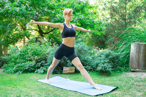Frau macht Yoga im Park, junges Mädchen macht verschiedene Wellness-Übungen, das Konzept eines gesunden Lebensstils und Gesundheitsfürsorge und ihr Körper - Foto, Bild
