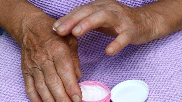 Yaşlı kadın parmakları kırışık avuç içi cildine nemlendirici krem sürerler. Yaşlı cilt bakımı kavramı - Fotoğraf, Görsel