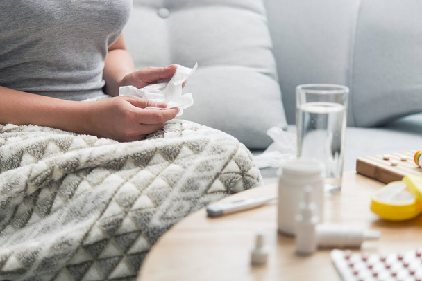 Egy megfázott, influenzás fiatal nő, vitaminokkal és tablettákkal szedi otthon az öngyógyszereit. orrfájás allergia miatt,. - Fotó, kép