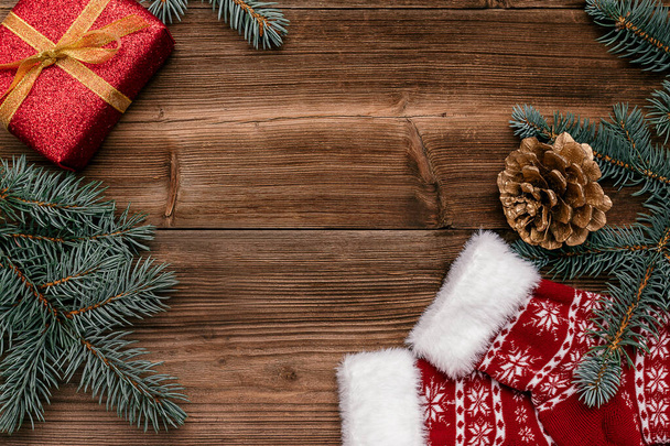 Kırmızı hediye kutusundan yapılmış Noel çerçevesi, mavi köknar ağacı dalları, koyu ahşap arka planda altın koni ve çoraplar. Noel arkaplanı. Yazı, yazı, üst görünüm, düz konum. - Fotoğraf, Görsel