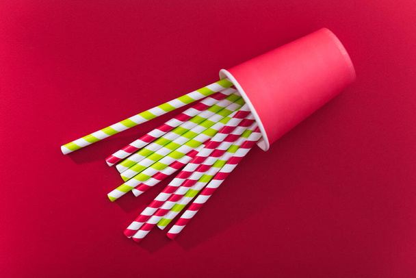 Bright colored cocktail straw on a color red background. recycling eco concept. minimal style. flat lay. top - Foto, imagen