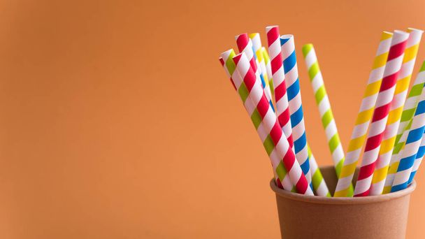 Luminoso paglia da cocktail colorato in tazza di carta su uno sfondo di colore. riciclo ecoconcetto. stile pop art. - Foto, immagini