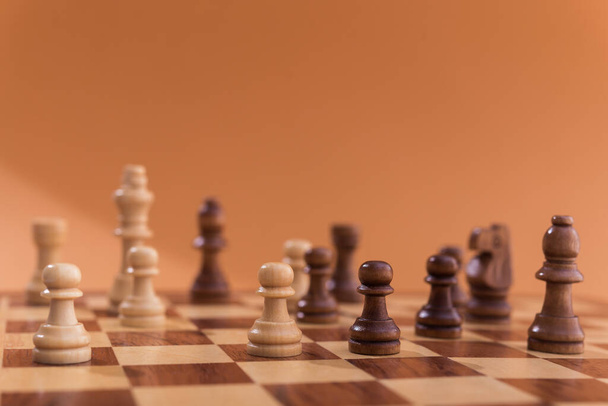 Деревянные шахматные фигуры на коричневом фоне.  - Фото, изображение