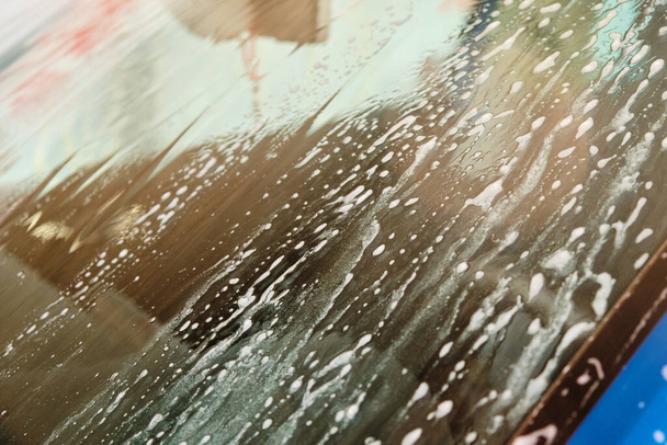 Přední čelní sklo v mýdle během mytí pěnou pod tlakem. Manuální nebo automatické mytí aut koncept. - Fotografie, Obrázek