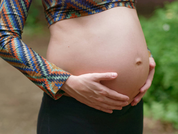Chiudere di incinta giovane donna moderna toccare la pancia all'aperto. - Foto, immagini