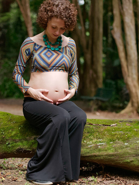 pregnant modern young woman touching her belly outdoors. - 写真・画像
