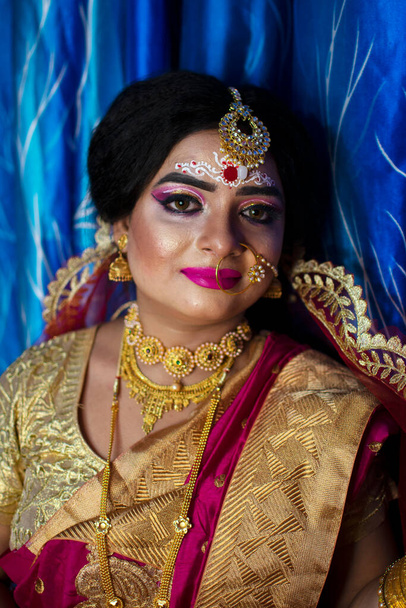 Portré egy aranyos indiai modell menyasszonyi megjelenés nehéz arany ékszerek és piros szári - Fotó, kép