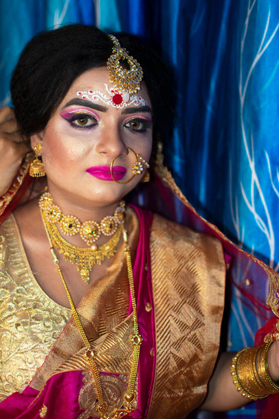 Πορτρέτο ενός χαριτωμένο ινδικό μοντέλο σε Νυφικό βλέμμα με βαριά χρυσά κοσμήματα και κόκκινο σάρι - Φωτογραφία, εικόνα