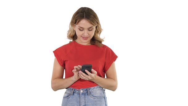Young beautiful woman in t shirt using her smartphone on white b - Фото, зображення