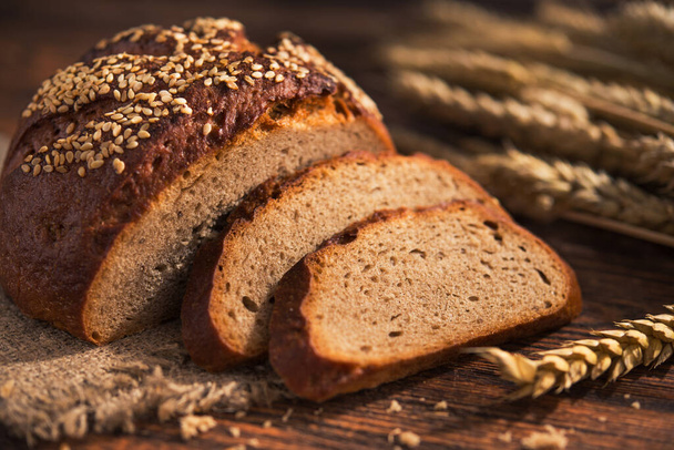 Tasty rye bread with sesame on a wooden background. - Photo, Image