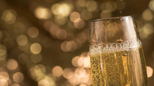 Großaufnahme eines Champagnerglases auf einem Bokeh-Hintergrund. Fröhliche Silvesterfeier. - Foto, Bild