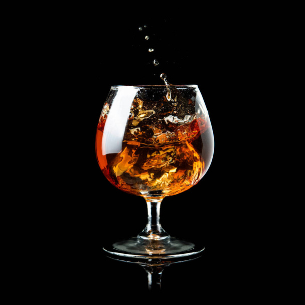 Cognac splash in glass on a black background - Foto, Imagem