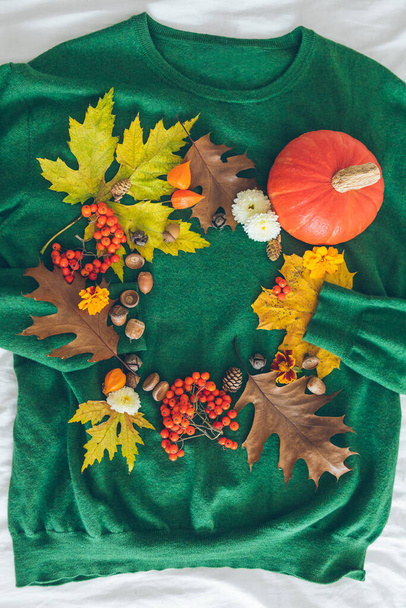 zielony sweter z jesiennymi żółtymi liśćmi i pomarańczową dynią. kartka z życzeniami. przestrzeń kopiowania - Zdjęcie, obraz