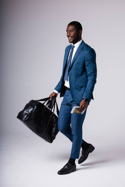 A man is standing in a blue business suit with a black travel bag. Isolated on white background - Photo, image