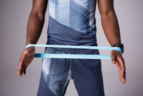 Black male athlete's hands stretching elastic band for training - Foto, imagen