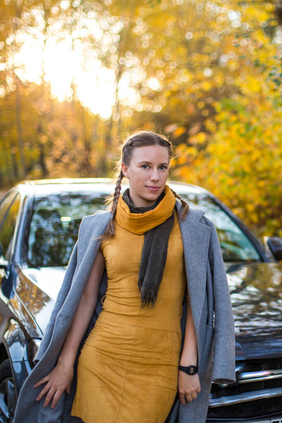 lány áll az autó mellett az őszi erdőben - Fotó, kép