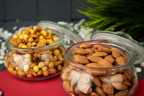 Almonds and assorted nuts such as chickpeas, corn and raisins, in glass jars for tasting at a party. - Photo, Image