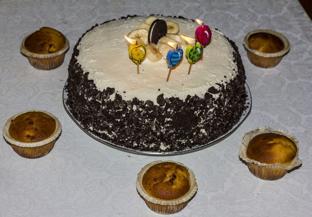 праздничный торт с четырьмя свечами, украшенными бананом и шоколадом
 - Фото, изображение