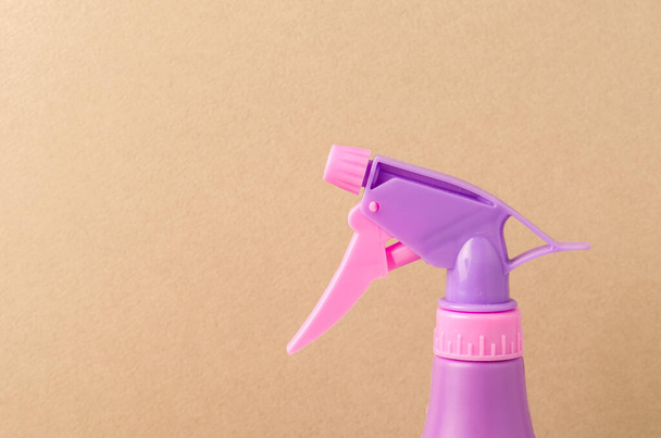 spray nozzle on a bottle/purple spray nozzle on a bottle on a light brown background. Copy space - Zdjęcie, obraz