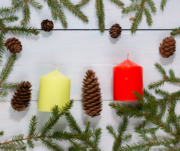 rami di un albero di Natale con coni e due candele gialle e rosse, la composizione di anno nuovo su uno sfondo bianco-azzurro di assi. Layout piatto, vista dall'alto, spazio di copia. - Foto, immagini