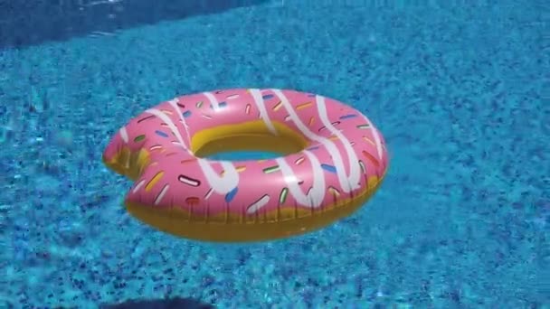 roze opblaasbare donut drijvend in zwembad 4K - Video