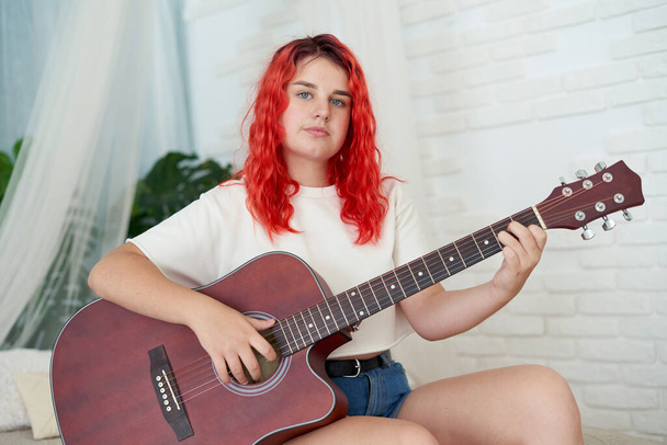 Teenage girl 12 years old holding a red acoustic guitar - Φωτογραφία, εικόνα