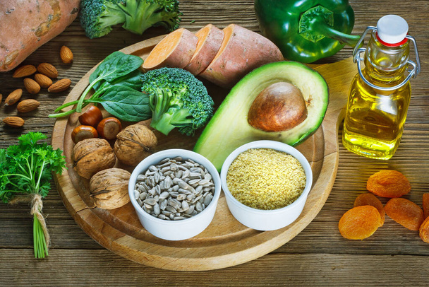 E-vitaminban gazdag élelmiszerek, például búzacsíra-olaj, szárított búzacsíra, szárított kajszibarack, mogyoró, mandula, petrezselyemlevél, avokádó, dió, édesburgonya, brokkoli, napraforgómag, spenót, zöld paprika - Fotó, kép
