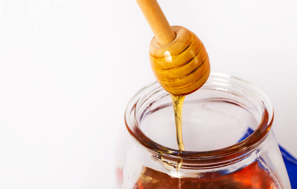 Honey with wooden honey dipper on white background in jar. - Photo, Image