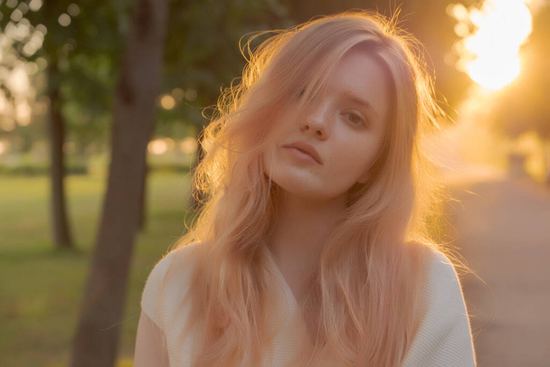 Outdoor fashion portrait of a  young woman with with straight blond hair at sunset - Фото, зображення