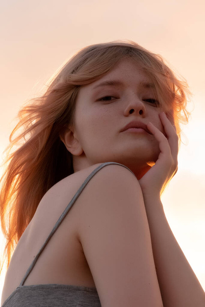 Outdoor fashion portrait of a  young woman with with straight blond hair at sunset - Foto, Bild