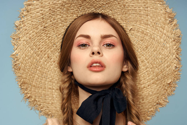 meisje in een stro hoed portret close-up pigtails leuk rood haar blauw achtergrond - Foto, afbeelding