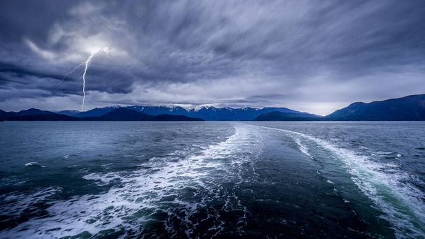 Dark Clouds ja Lightning Strike in the Wake of a Ferry välillä Horseshoe Bay ja Sechelt Brittiläisessä Kolumbiassa, Kanadassa - Valokuva, kuva