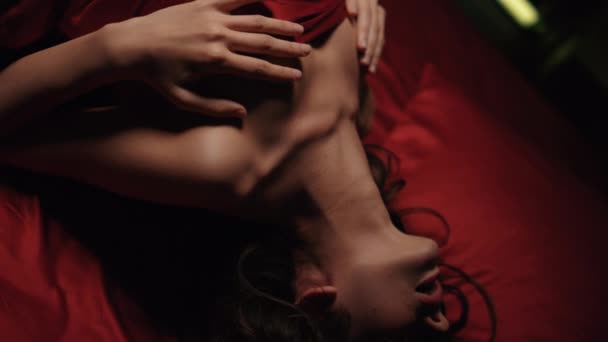 Nahaufnahme nackte Frau posiert im Bett. Sexy Mädchen spielt sich auf rotem Seidentuch. - Filmmaterial, Video
