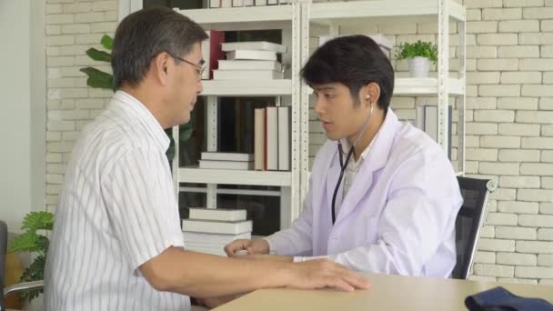  nuori aasialainen lääkäri käyttää stetoskooppi tutkia ihmisiä, joilla on sairaus klinikalla. terve vanhempi mies konsultointi psykiatri Terveystarkastus. Konsepti Lääketieteellinen neuvonta, terapia, Mielenterveyspotilaat sairaalassa - Materiaali, video
