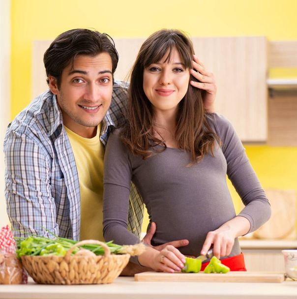Man and pregnant woman preparing salad in kitchen - Фото, зображення