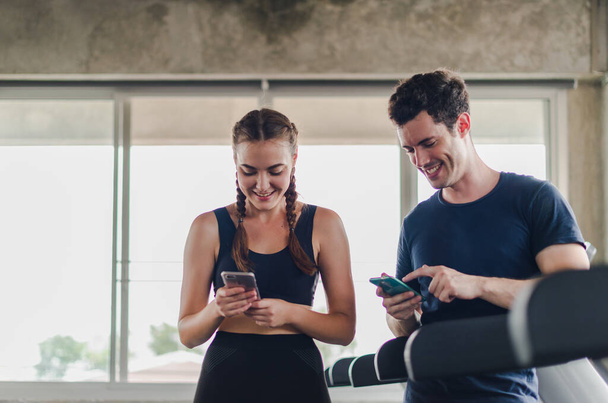 Couples exercise at the gym. Couple having fun playing with smartphones Near the exercise machine. - Fotó, kép