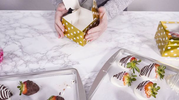 Schritt für Schritt. Verpackung von Schokolade eingetauchten Erdbeeren in einer Pappschachtel für ein Geschenk. - Foto, Bild