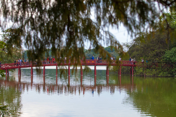  Hanoi, Vietnam - October 21, 2019 : Hanoi red bridge. The wooden red painted bridge over the Hoan Kiem Lake connects the shore and the Jade Island on which Ngoc Son Temple stands. - Photo, Image